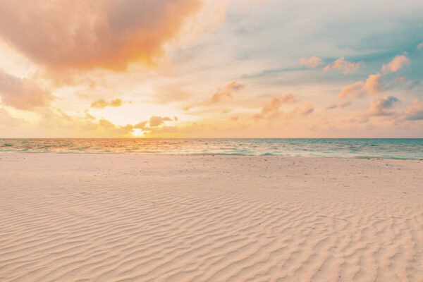 Une plage de sable avec des vagues et un coucher de soleil Une plage de sable avec des vagues et un coucher de soleil