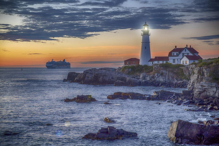 Phare sur un rivage rocheux avec un bateau de croisière en arrière-plan