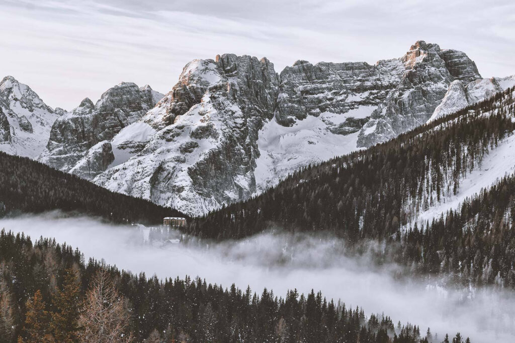 Chaîne de montagnes enneigées avec des arbres et un bâtiment Chaîne de montagnes enneigées avec des arbres et un bâtiment