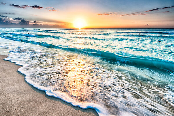 A beach with waves and a sunset
