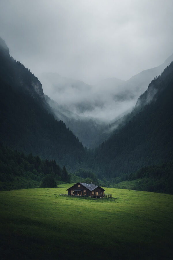 Maison dans un champ avec des montagnes en arrière-plan Maison dans un champ avec des montagnes en arrière-plan